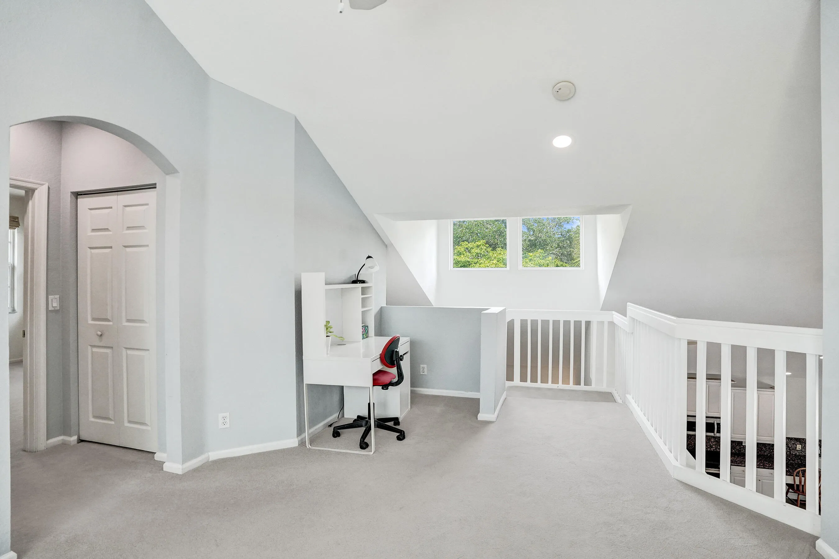 Upper level with arched doorway, light gray carpeting, and white railings