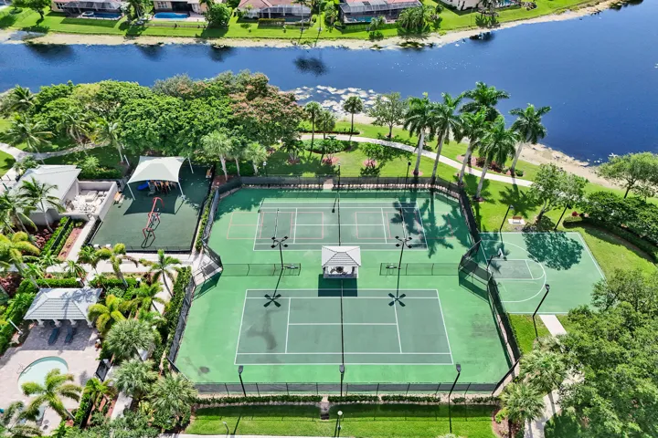 Tennis courts with perimeter fencing, covered structures, and adjacent playground area
