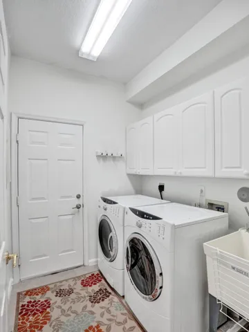 Dedicated laundry area featuring a utility sink, white cabinetry, and a bright overhead light fixture