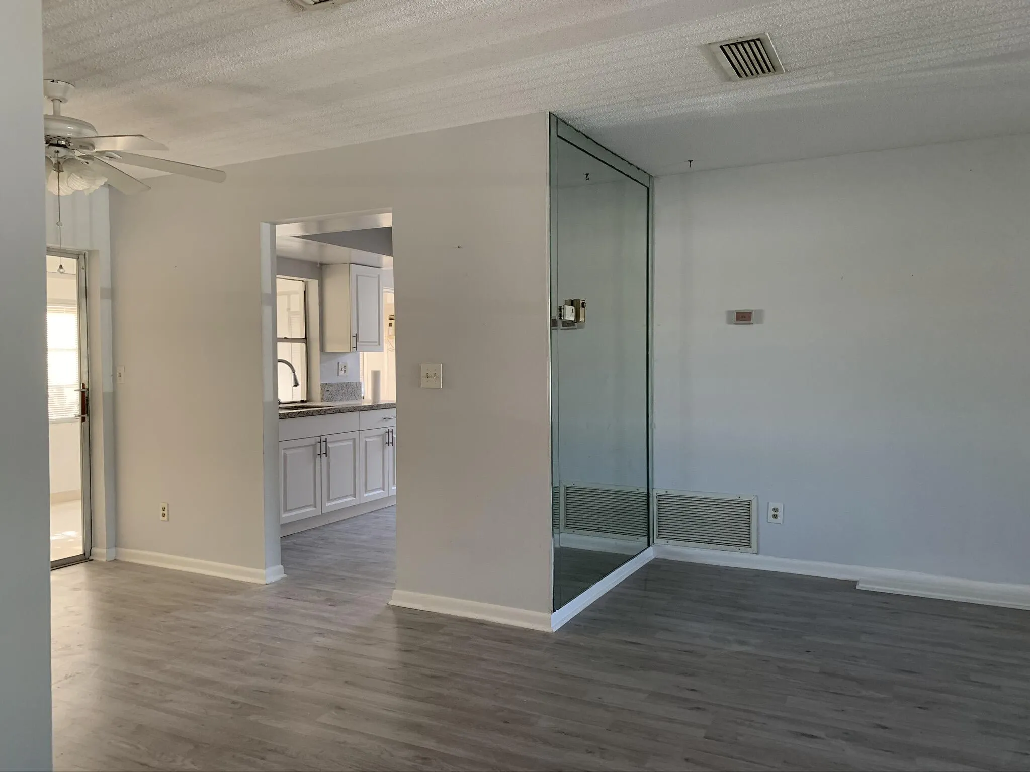 Wood-finish flooring throughout, bright white walls, and a ceiling fan with integrated lighting