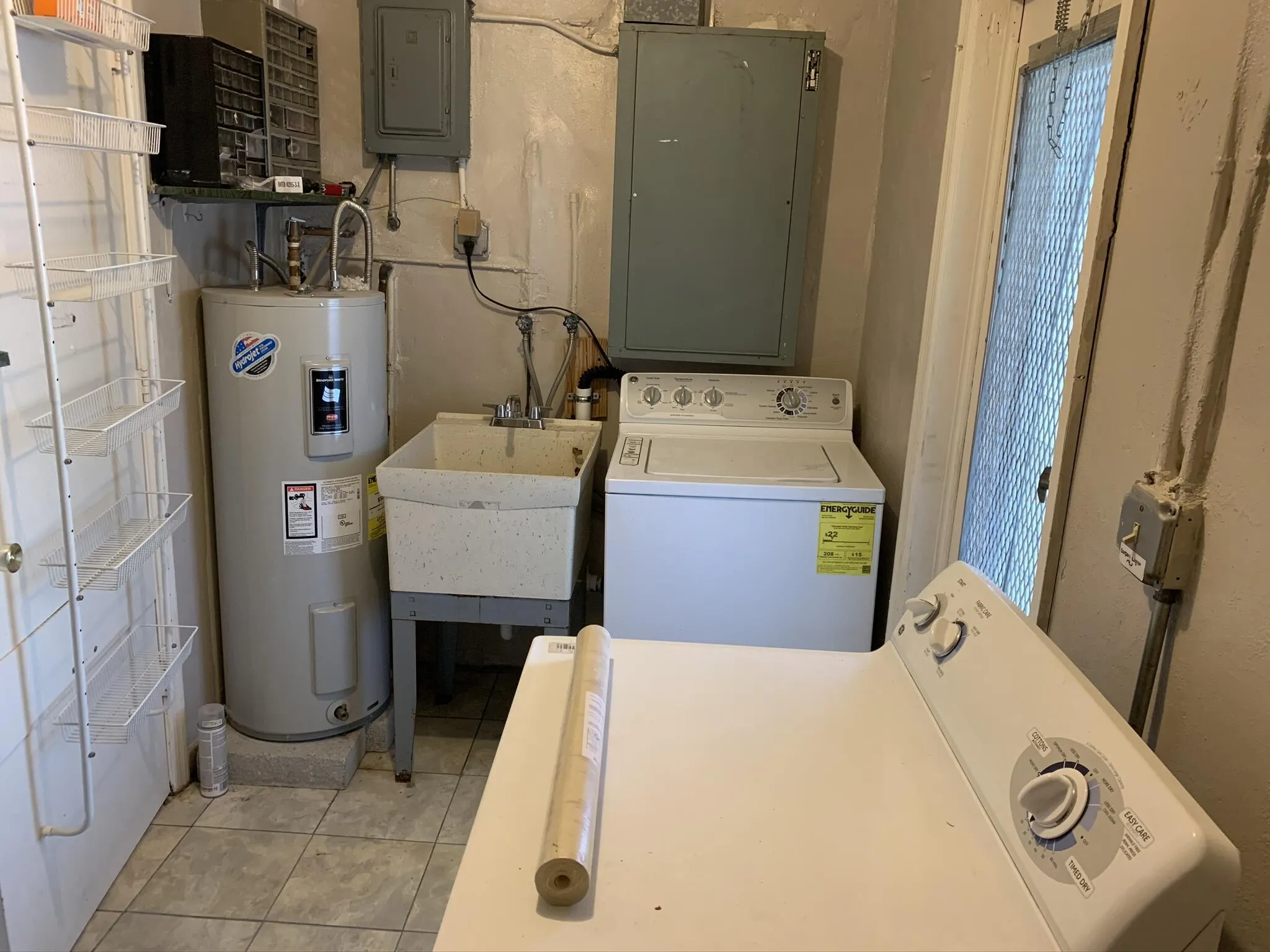 Utility area featuring a water heater, a utility sink, and tiled flooring