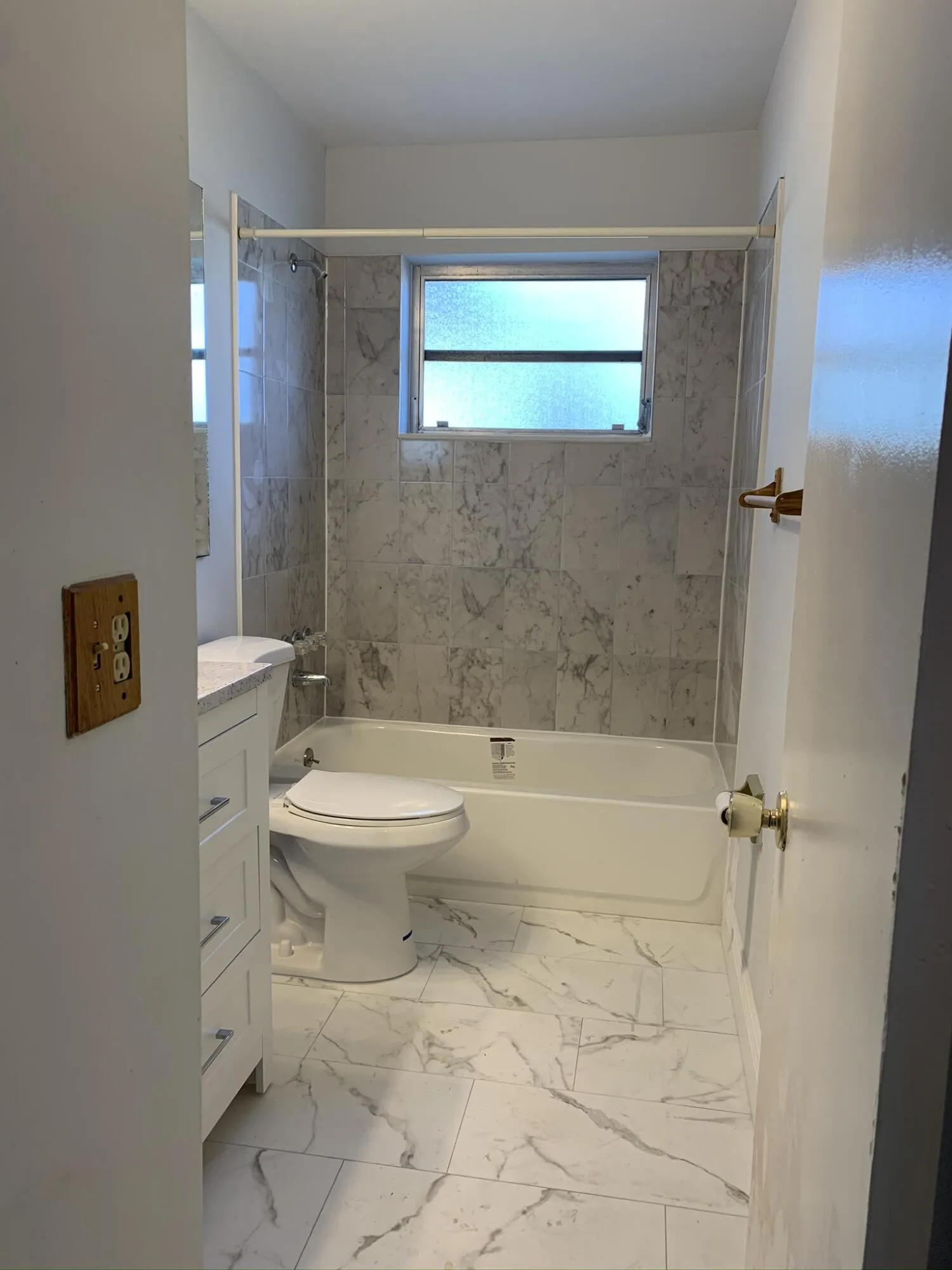 Shower/tub combination with ceramic tile surround, matching ceramic tile flooring, and a single window with privacy glass
