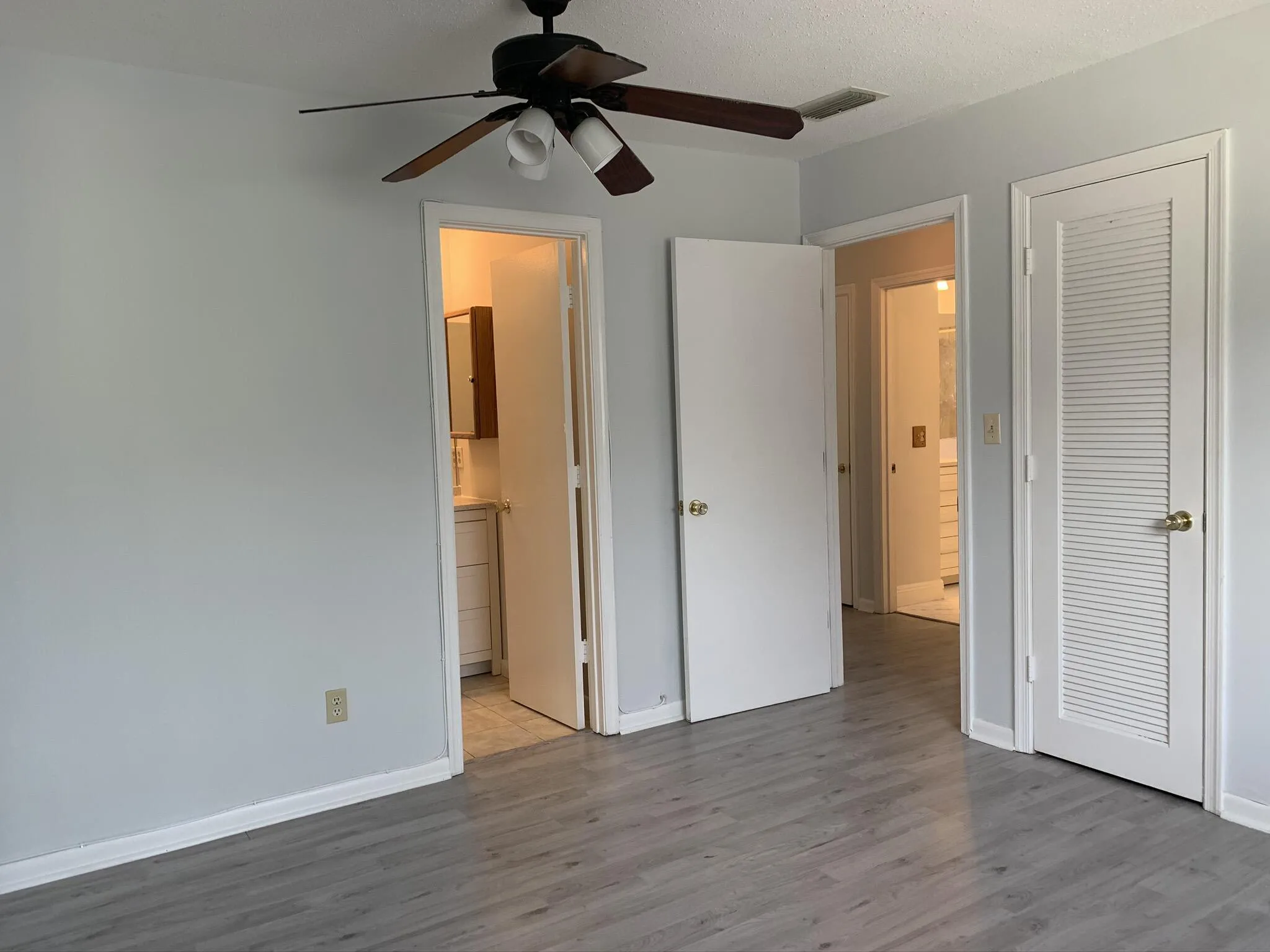 Wood-finish flooring with light gray walls and a ceiling fan