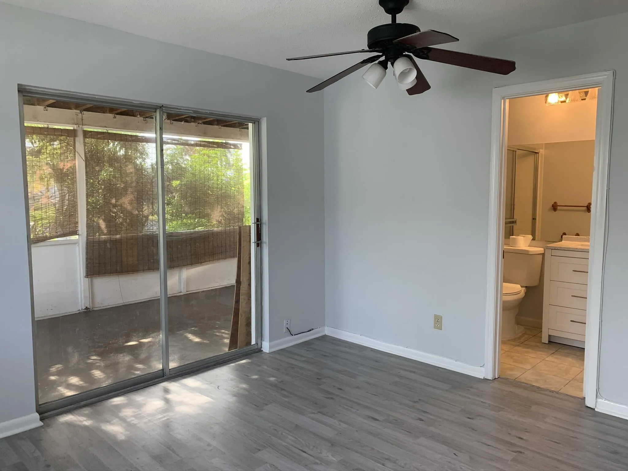 Wood-finish flooring, a ceiling fan with integrated lighting, and a sliding glass door opening to a screened patio