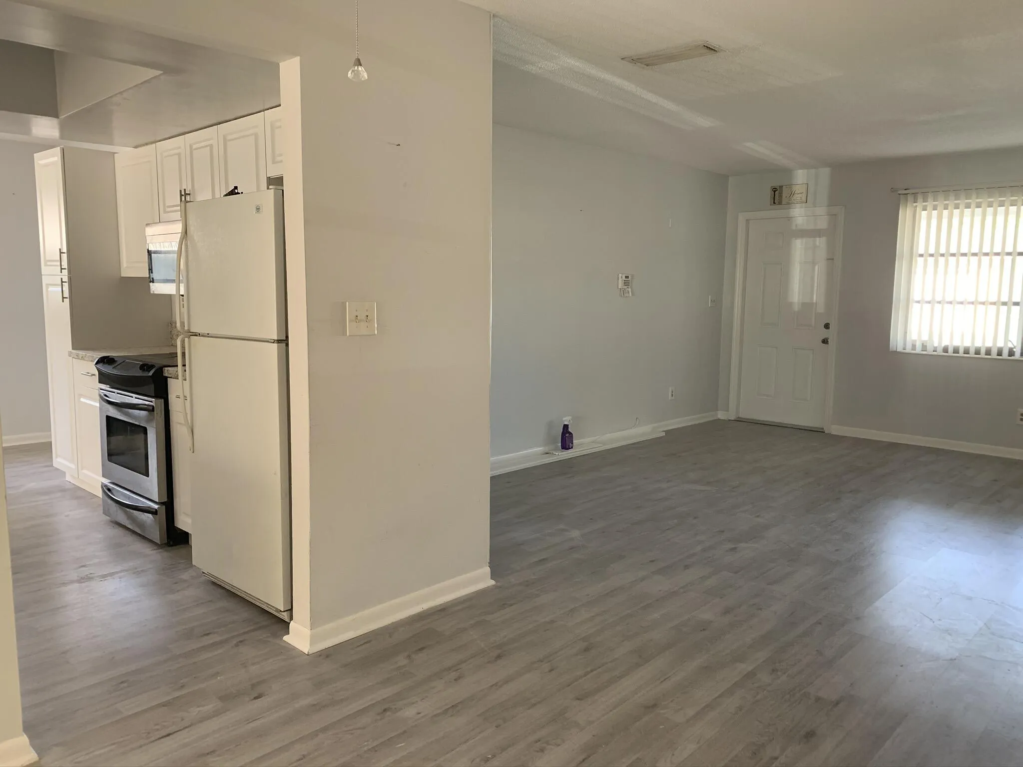 Kitchen area featuring white cabinetry, stainless steel oven, and light-toned wood-finish flooring throughout