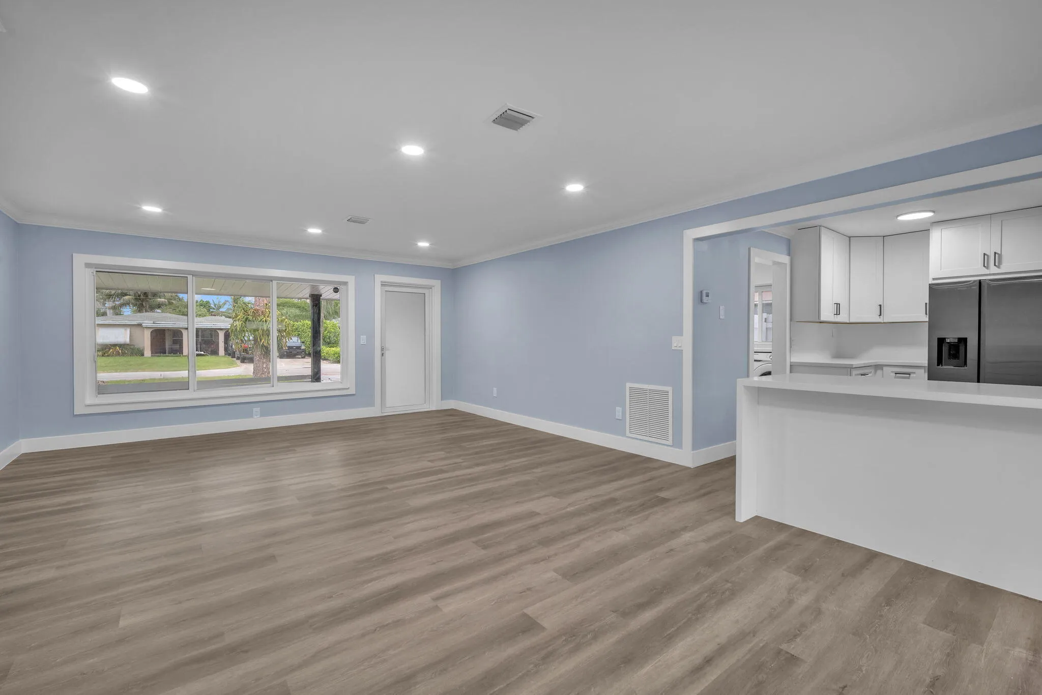 Open-concept living space with wood-finish flooring, recessed lighting, and a white breakfast bar