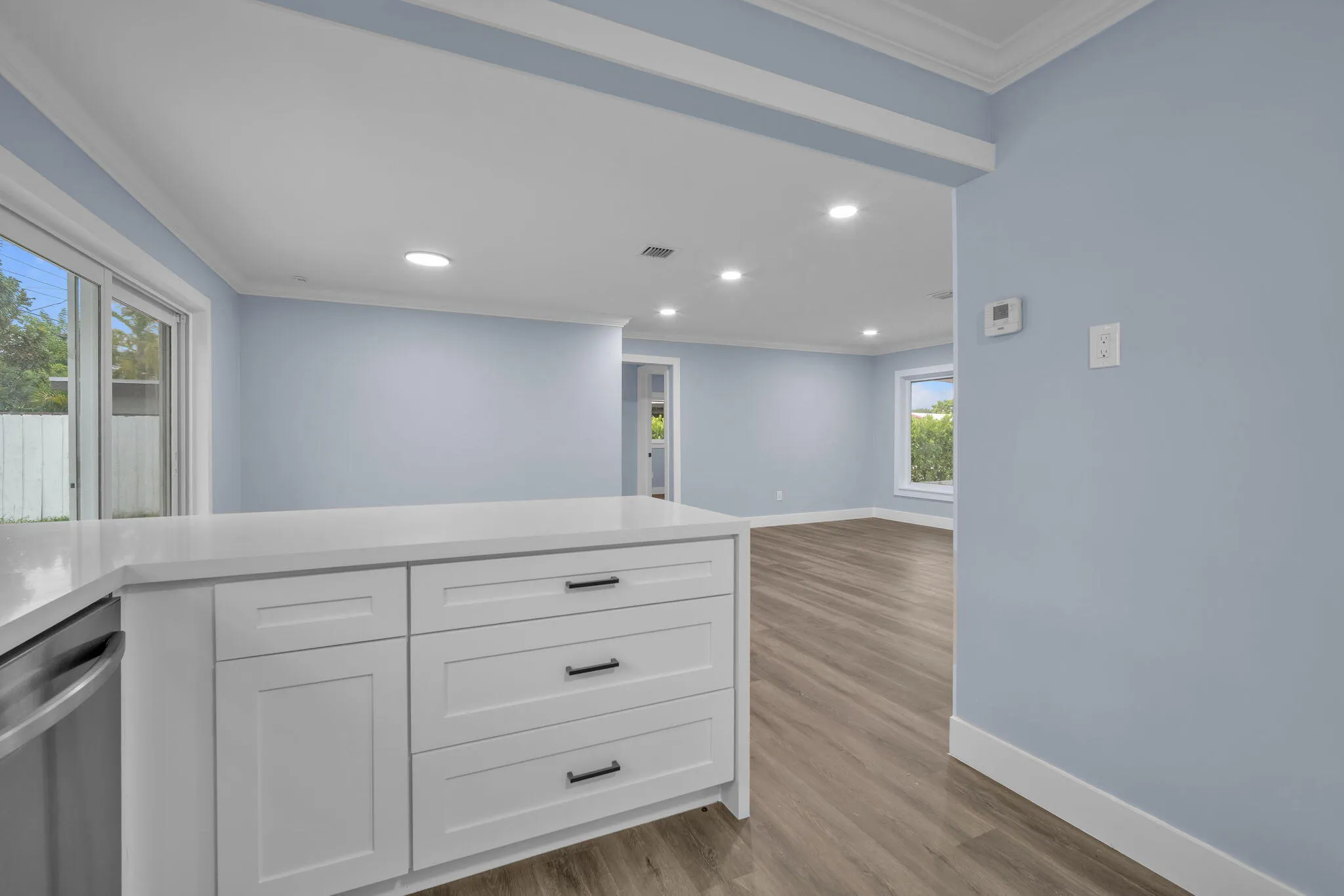 White kitchen island with a light-toned countertop, recessed lighting, wood-finish flooring, and white trim