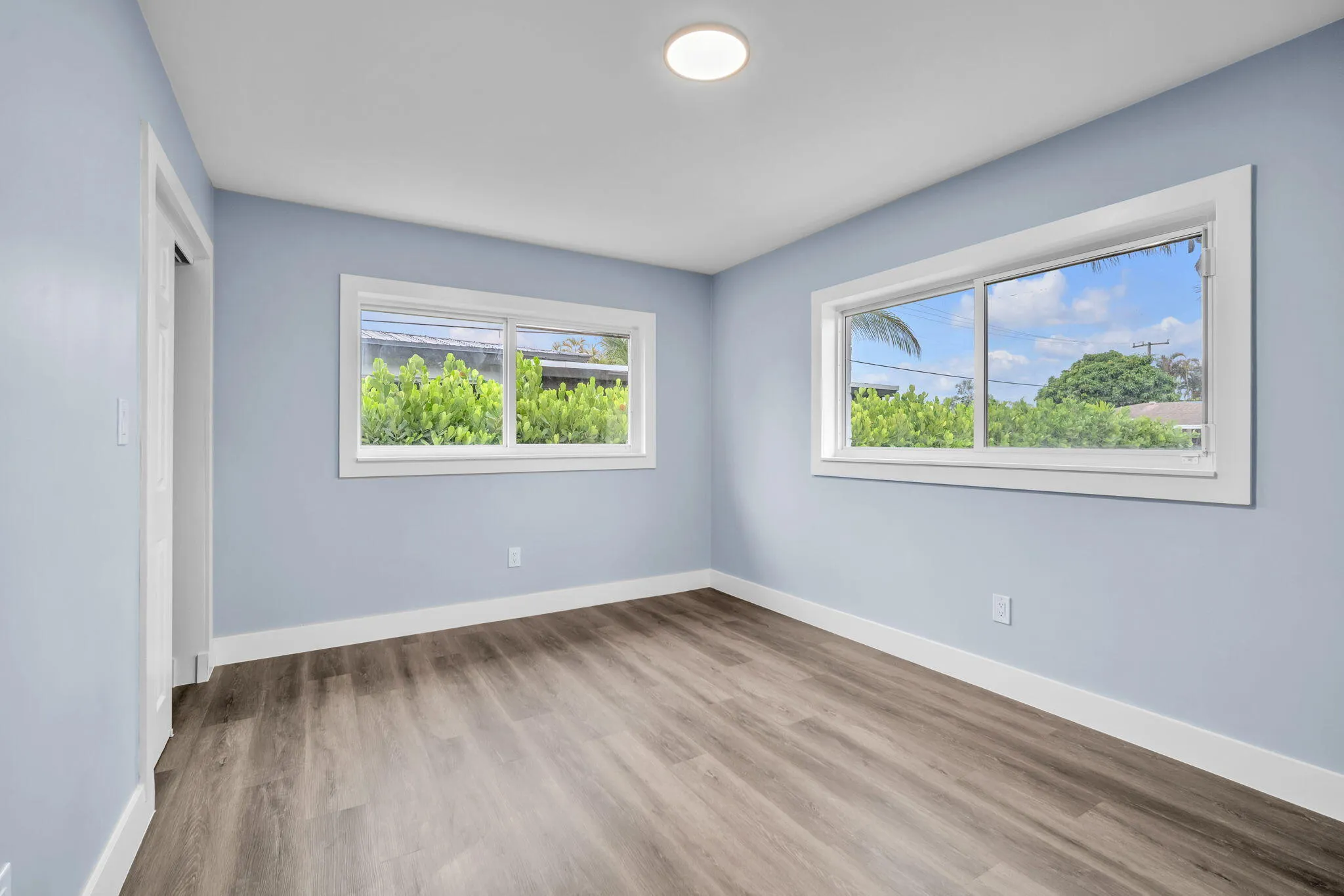 Wood-finish flooring, light blue walls, and white trim