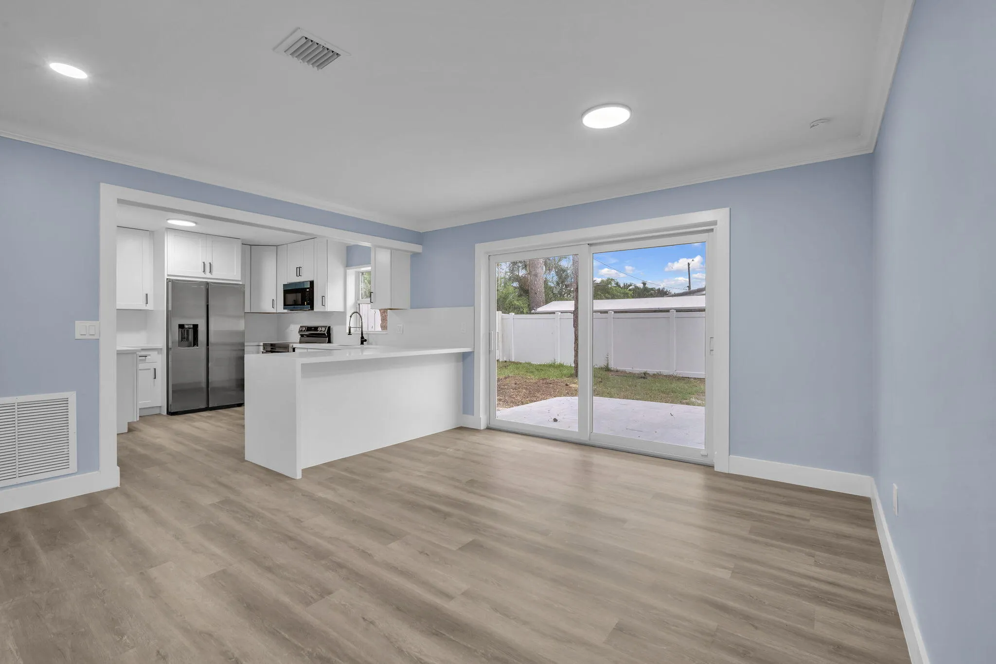 Open-concept living area featuring wood-finish flooring, recessed lighting, and a sliding glass door
