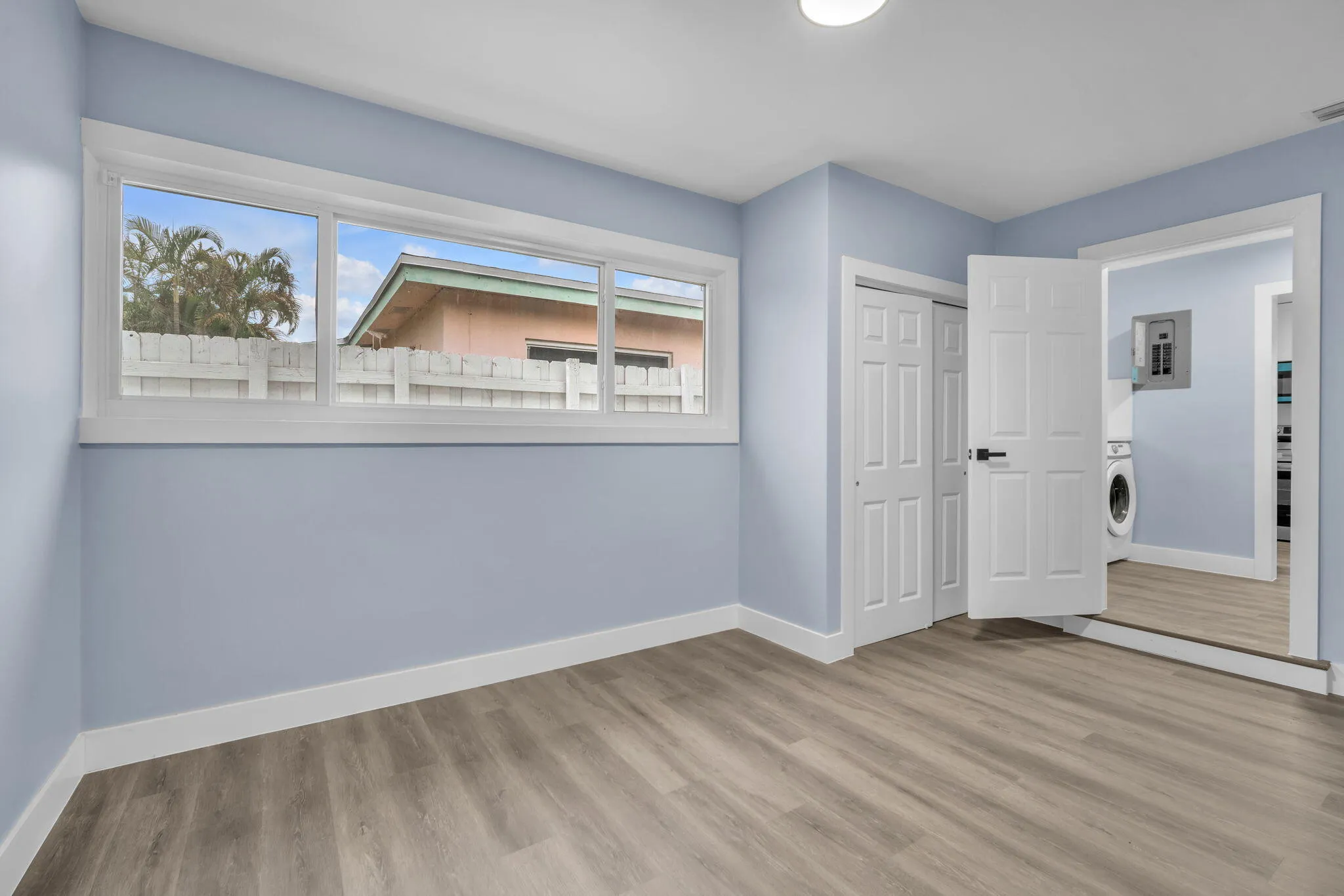 Light blue interior walls with white trim, wood-finish flooring, recessed lighting, and a white six-panel door