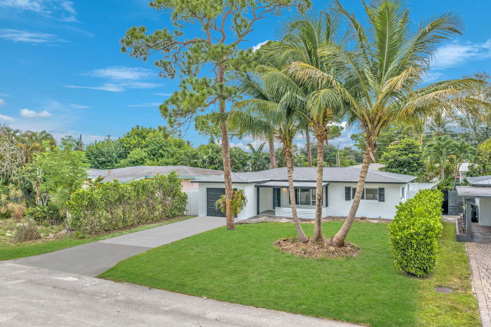 White exterior with a dark roof, attached garage with a dark door, and a concrete driveway