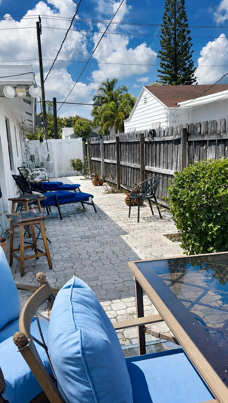 Pavered patio area with perimeter fencing and exterior wall-mounted lighting
