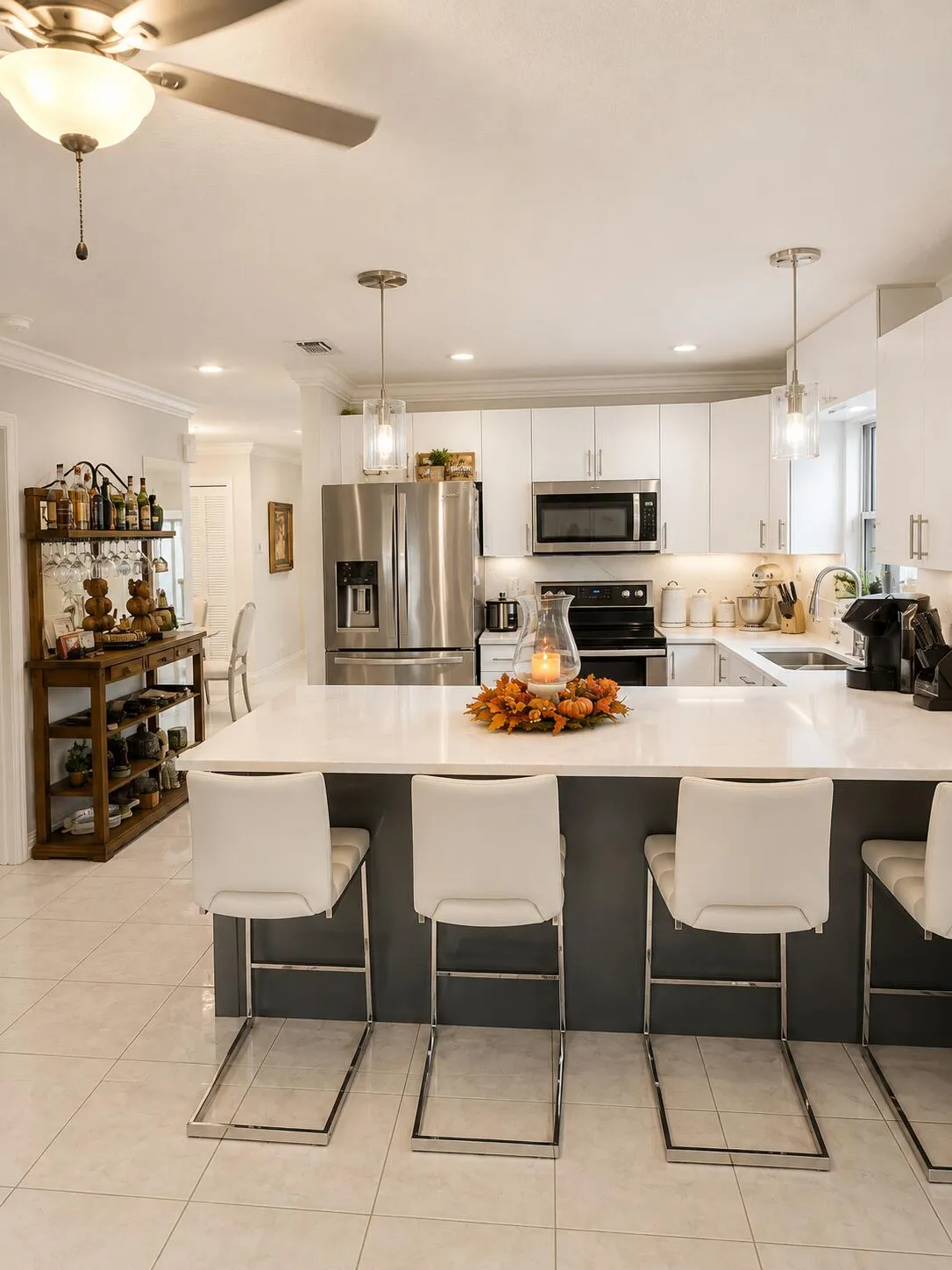 Kitchen featuring a large island with a light-colored countertop, white cabinetry, stainless steel appliances, and tile flooring