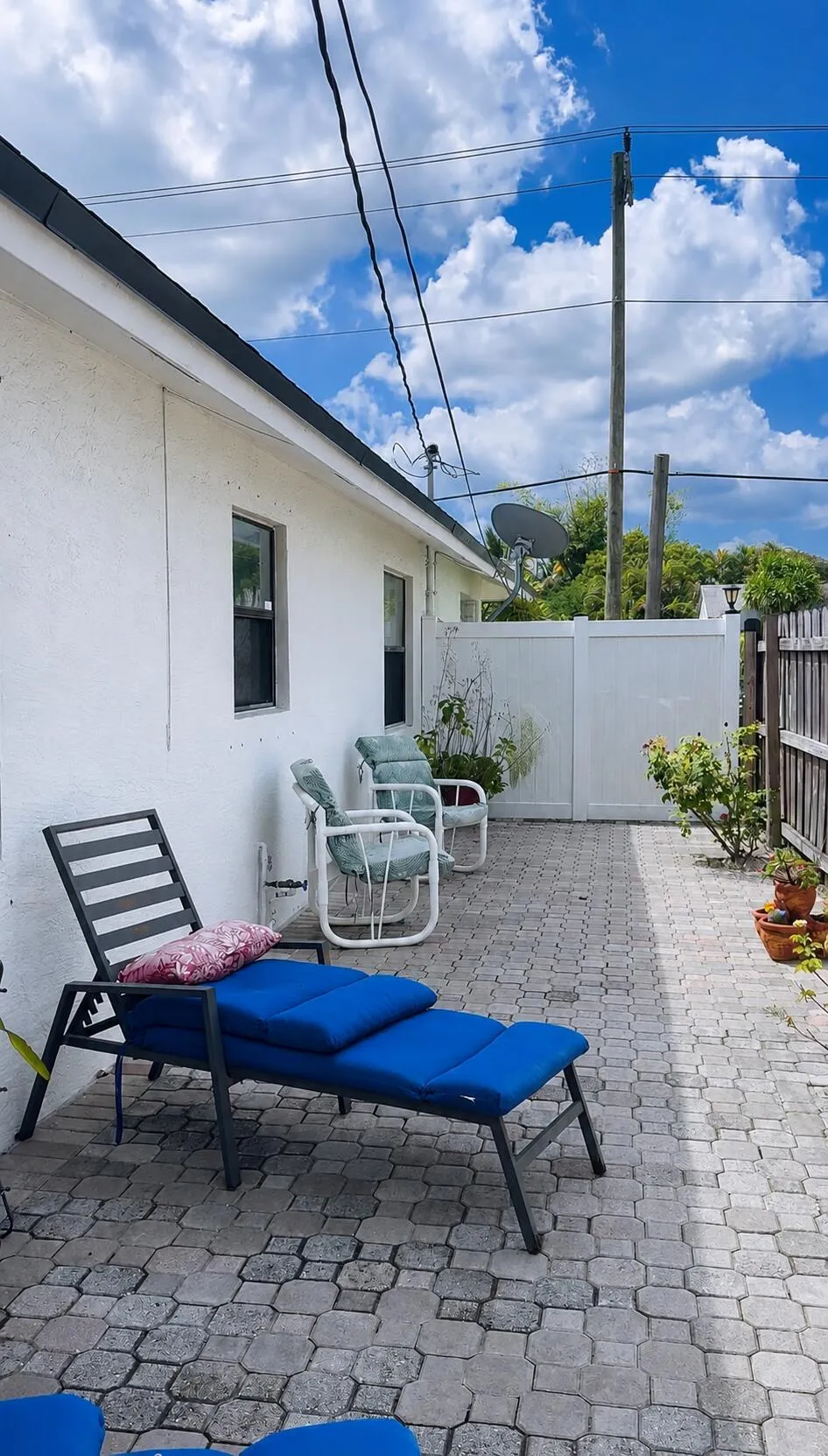 Paved patio area, white exterior siding, and white privacy fencing