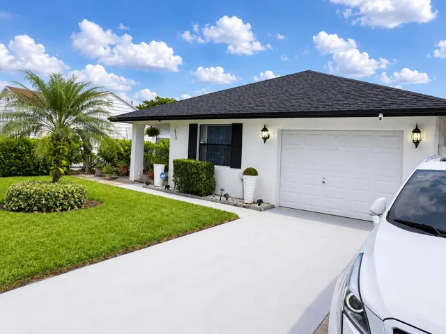 White exterior with dark roof shingles, an attached garage, and a concrete driveway
