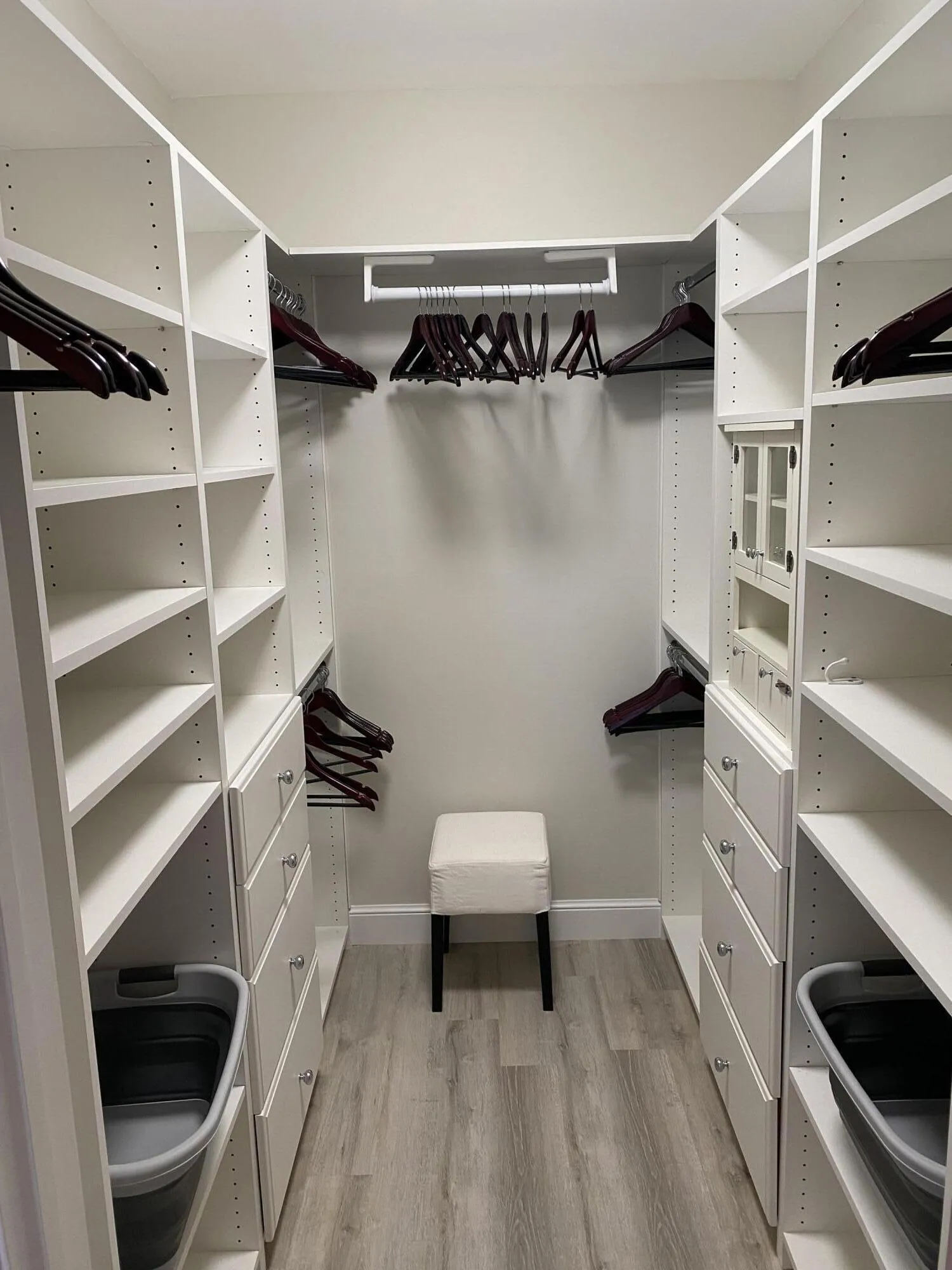 Custom closet system with integrated shelving, multiple hanging rods, and built-in drawers