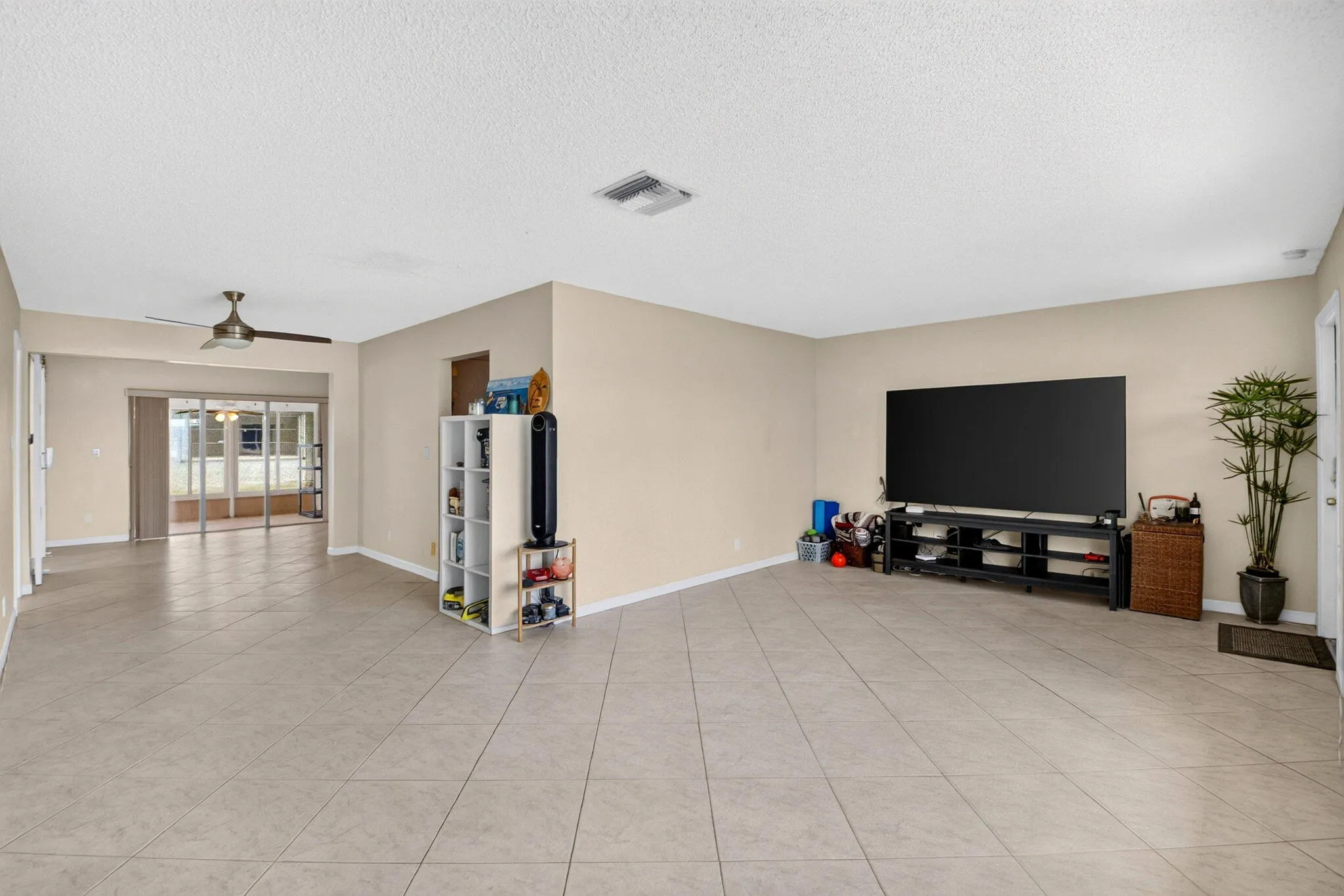 Expansive room featuring neutral-toned walls, tile flooring, and a ceiling fan
