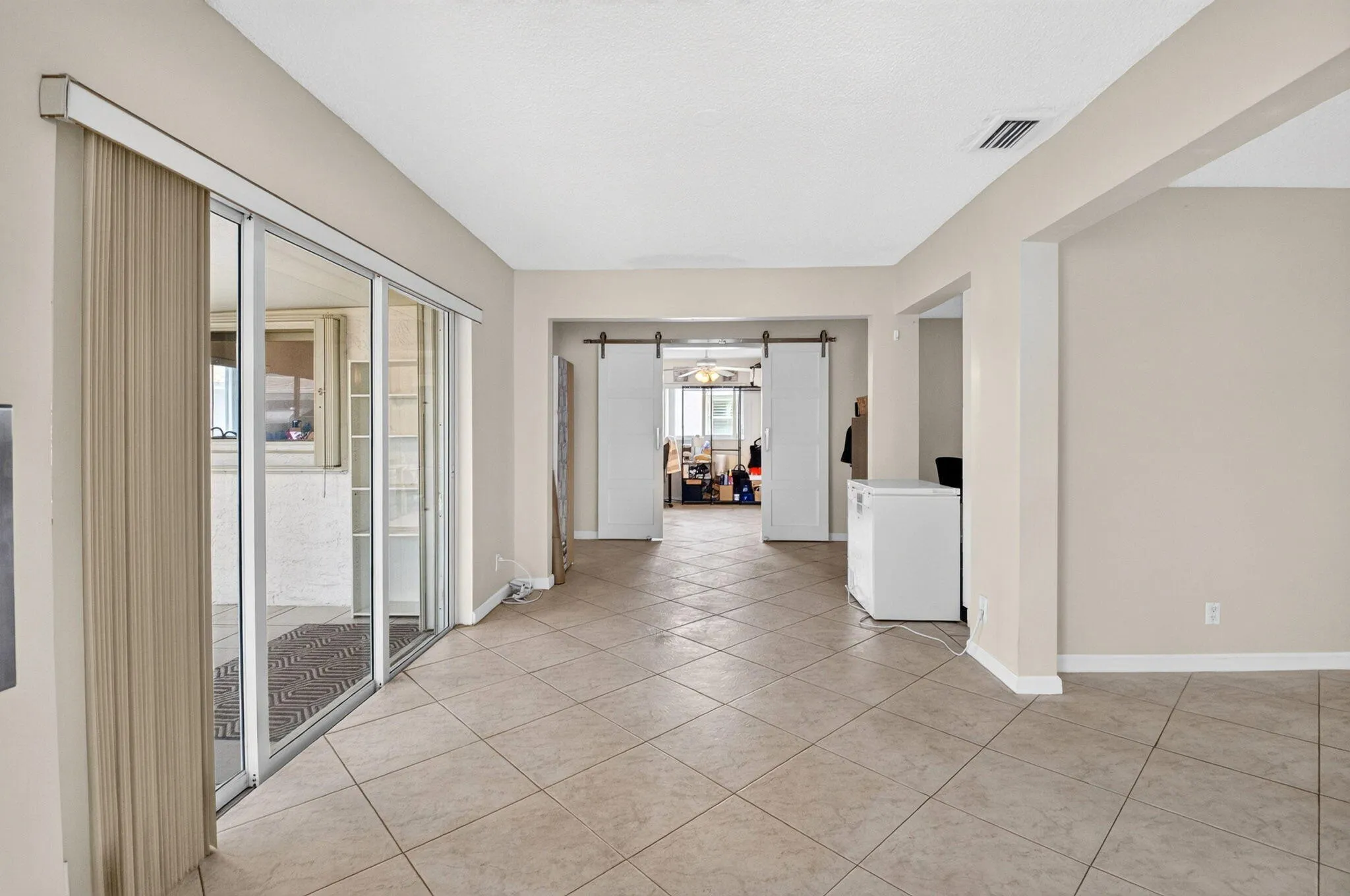 Neutral tone wall paint, tile flooring, sliding glass door, white barn doors, recessed lighting