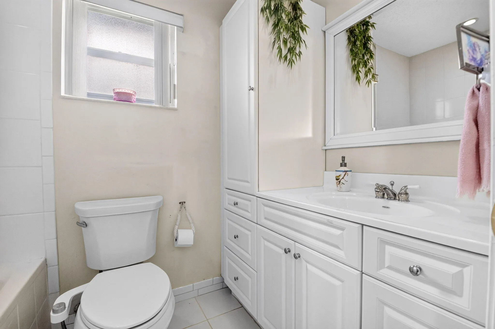 White vanity with panel-front cabinetry, integrated sink, and chrome fixtures