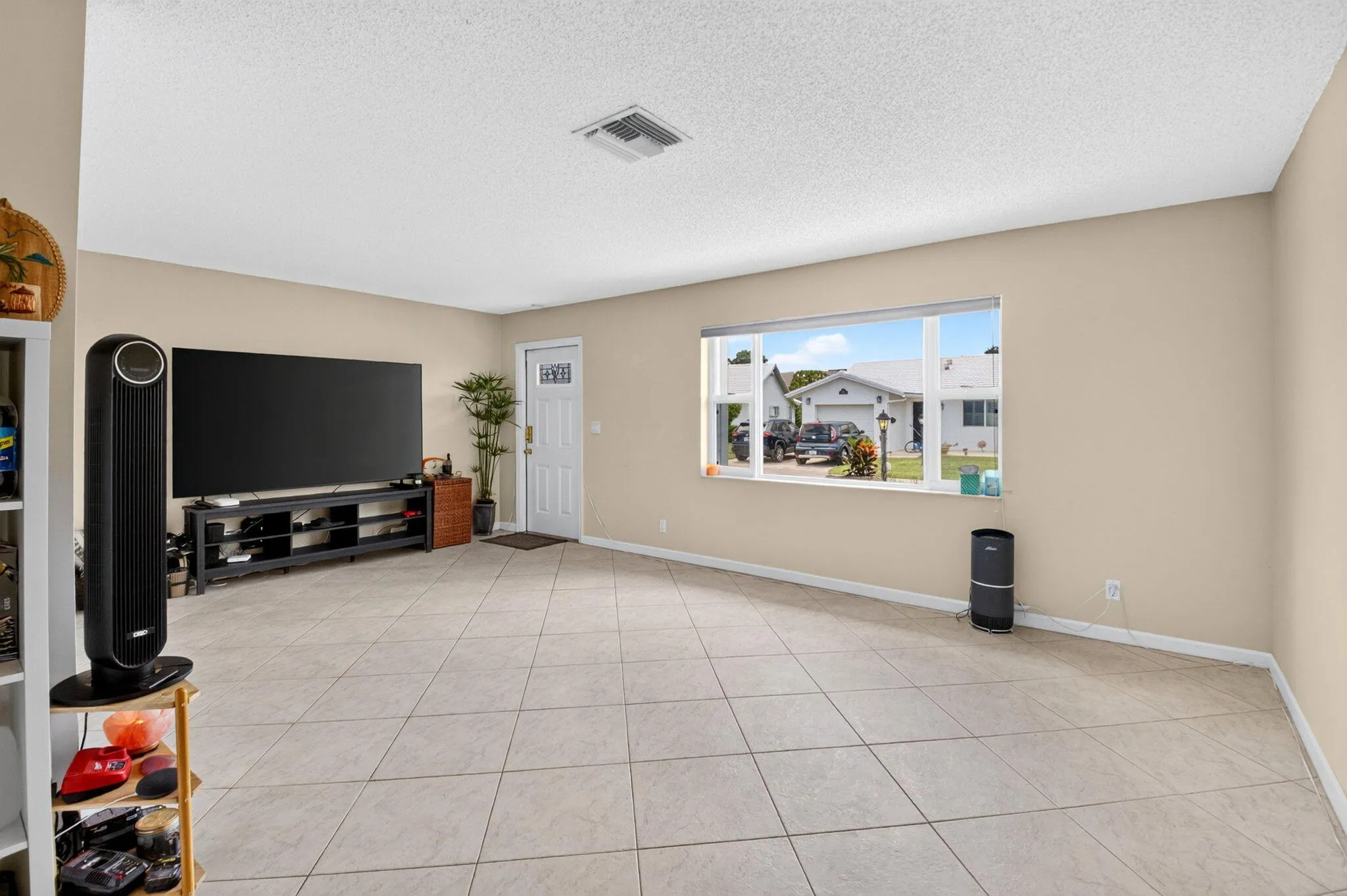 Neutral-toned walls, tile flooring, and a white front entry door with a clear glass insert