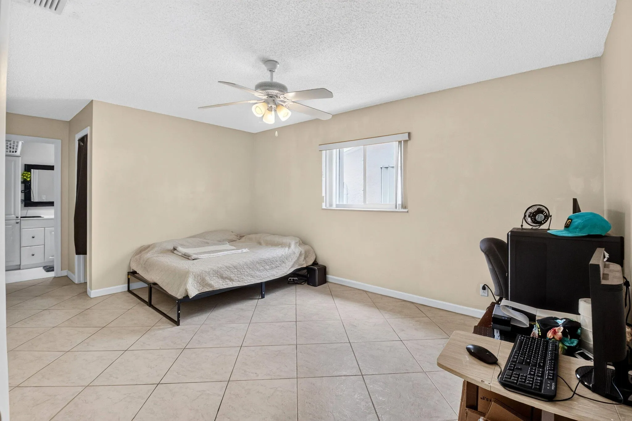 Recessed window, tile flooring, ceiling fan with integrated lighting, neutral wall tones, and an open doorway to a vanity area