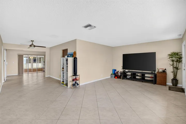 Expansive room featuring neutral-toned walls, tile flooring, and a ceiling fan