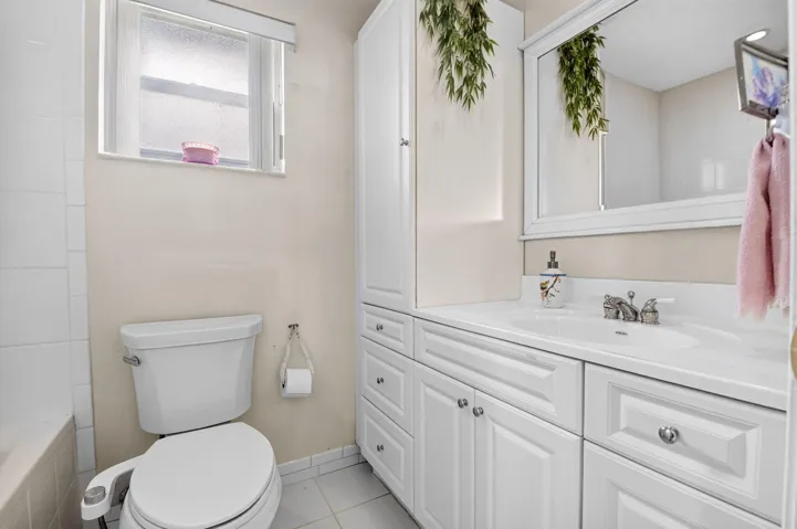 White vanity with panel-front cabinetry, integrated sink, and chrome fixtures