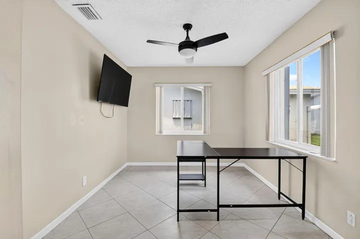 Recessed ceiling fan with integrated lighting, multiple windows providing natural illumination, tiled flooring, and neutral wall paint
