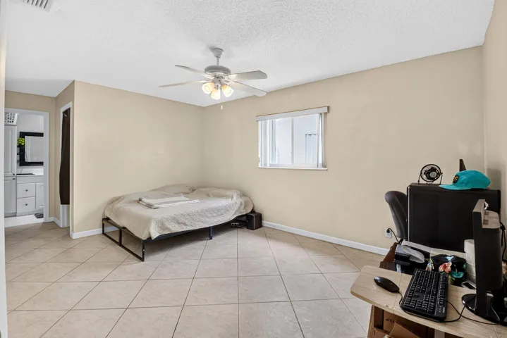 Recessed window, tile flooring, ceiling fan with integrated lighting, neutral wall tones, and an open doorway to a vanity area
