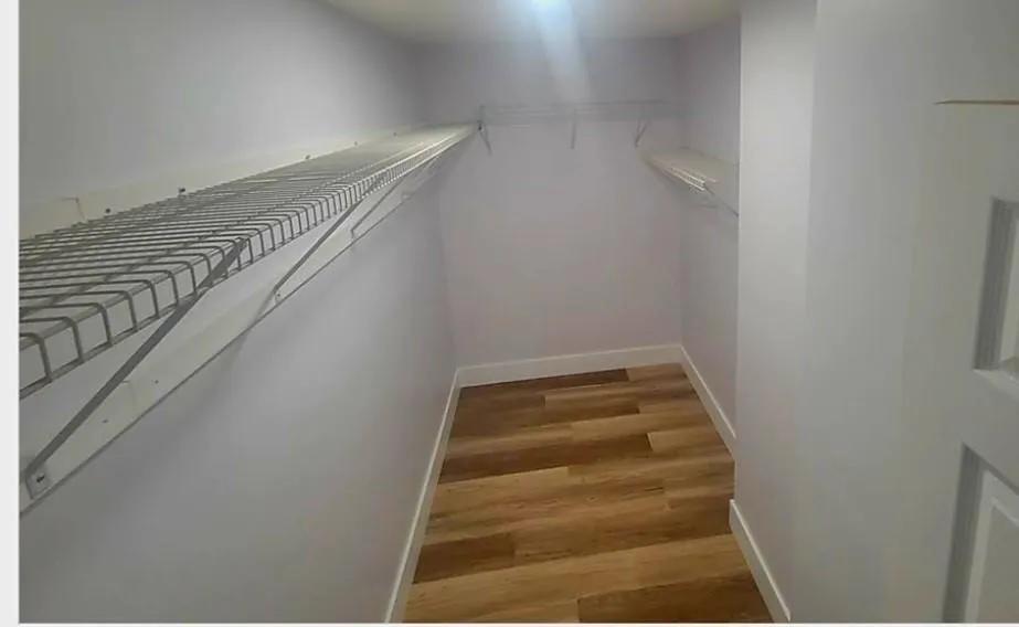 Recessed lighting, wood-finish flooring, white wire shelving, and crisp white trim