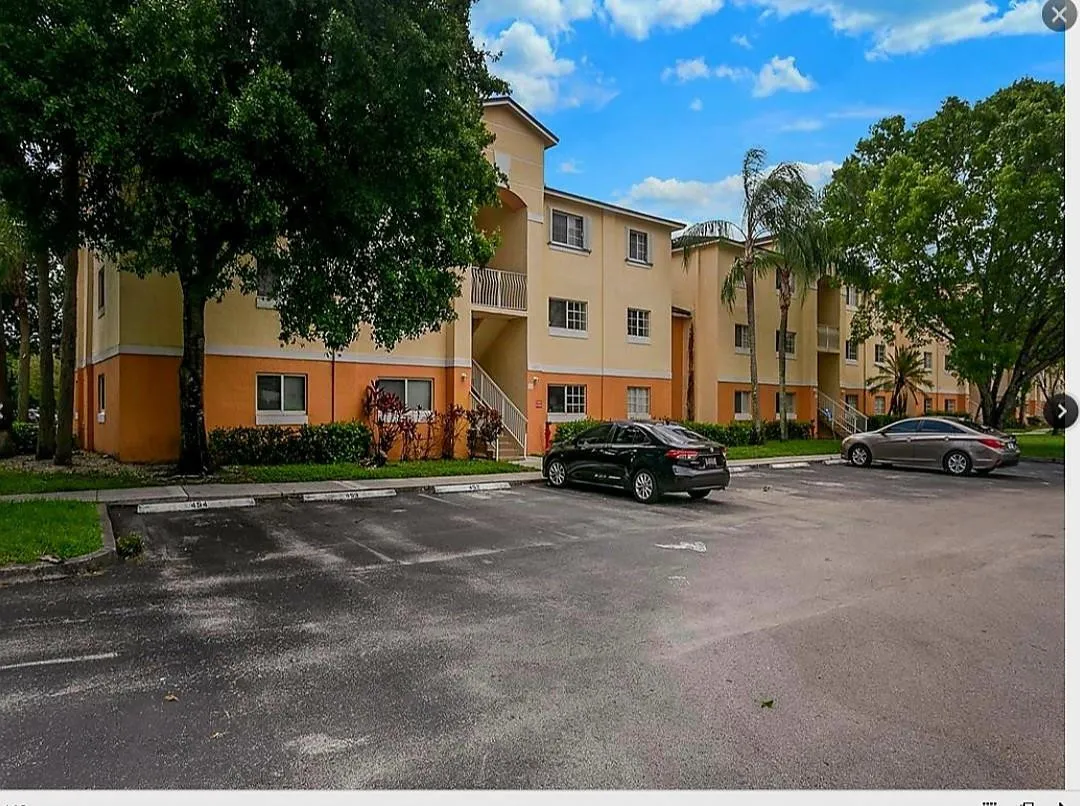 Multi-story building with a light-colored stucco exterior and contrasting orange accent base