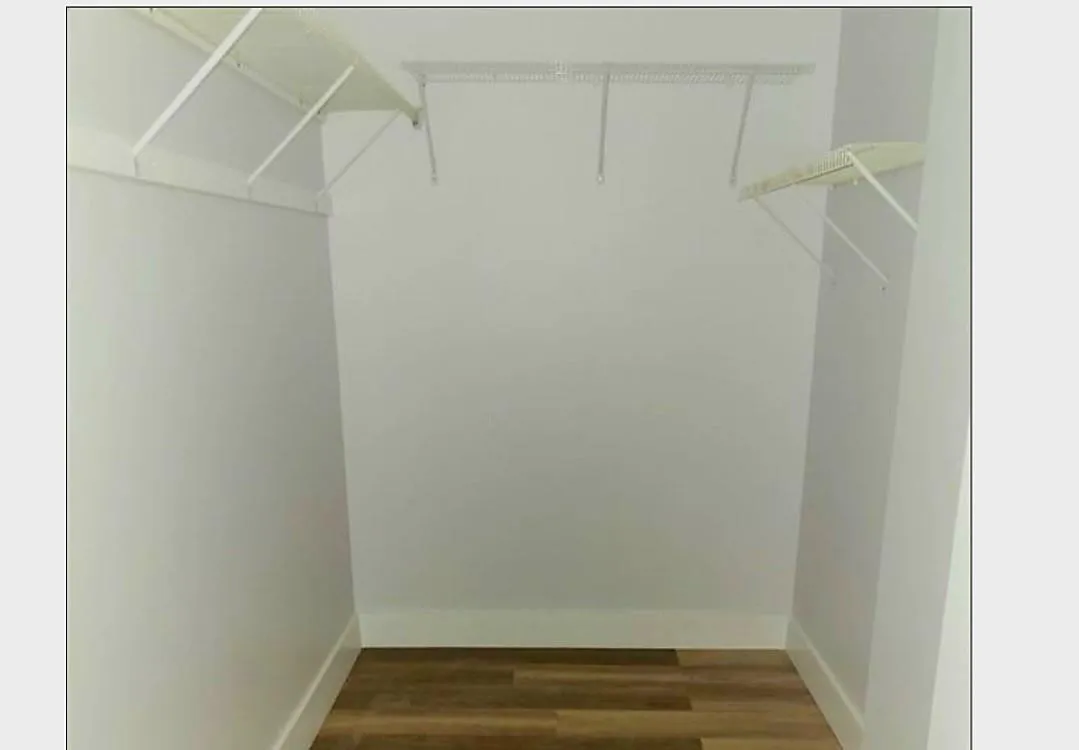 Walk-in closet featuring white wire shelving and wood-finish flooring
