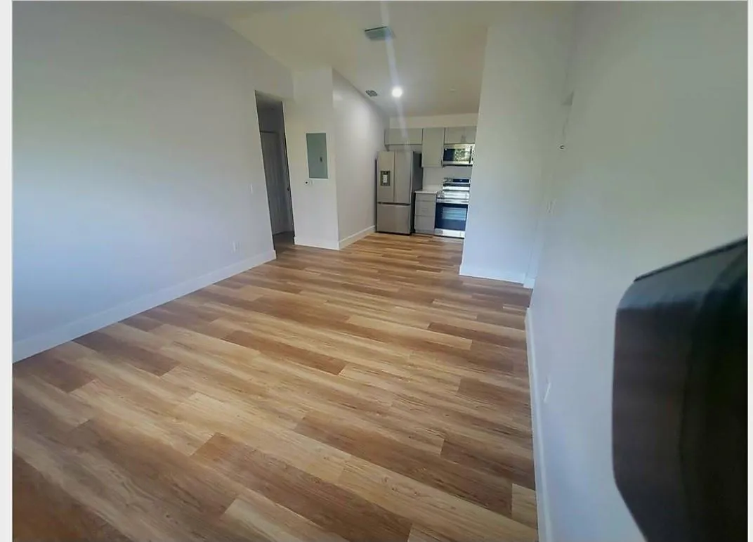 Wood-finish flooring throughout, bright white walls, and a recessed lighting fixture