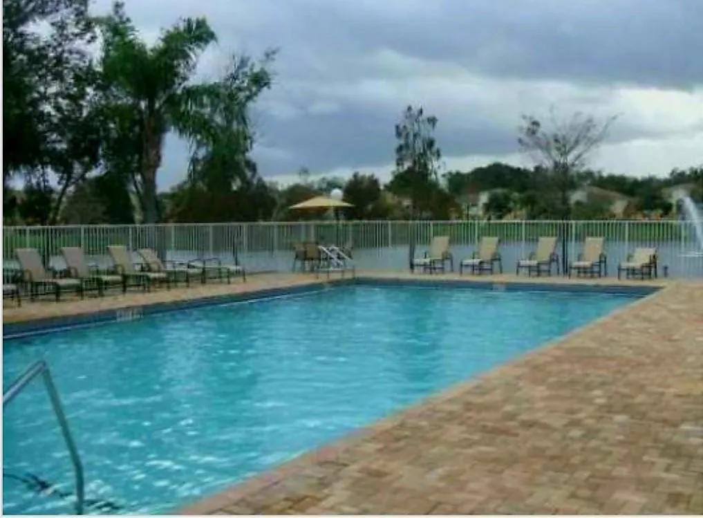 Community swimming pool with a brick paver deck, perimeter fencing, and surrounding landscaping
