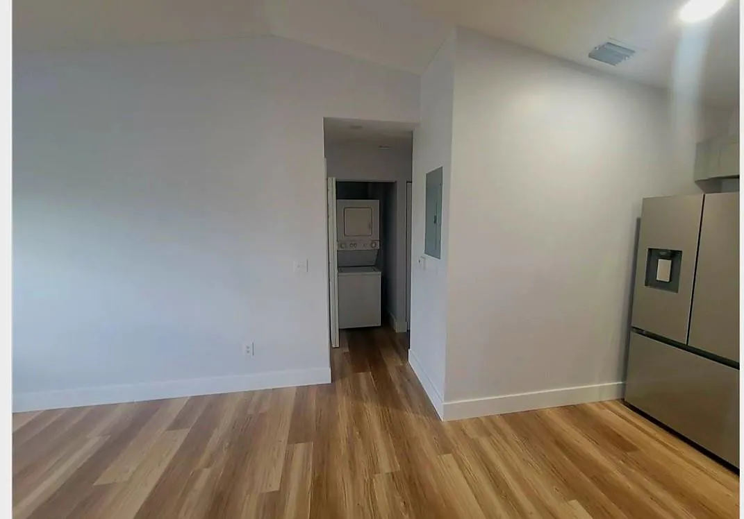 Wood-finish flooring, vaulted ceiling, stainless steel refrigerator, and in-unit stacked washer and dryer