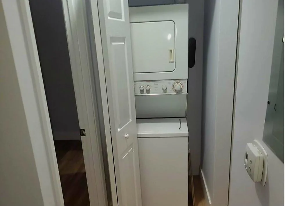 Stacked washer and dryer unit within a dedicated closet, featuring louvered bi-fold doors