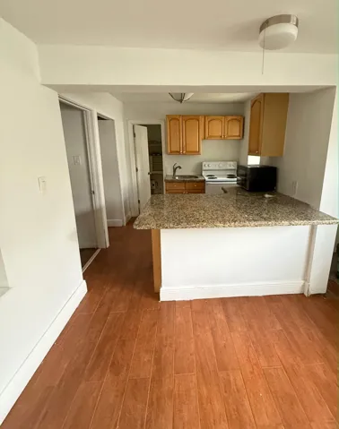 Kitchen featuring wood-tile finish flooring, granite-style counter tops, and natural wood cabinetry