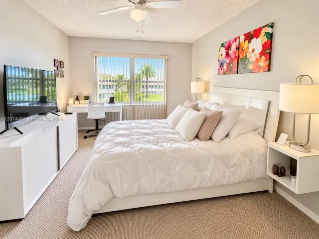 Neutral-toned carpeted flooring, ceiling fan with light fixture, and window with vertical blinds