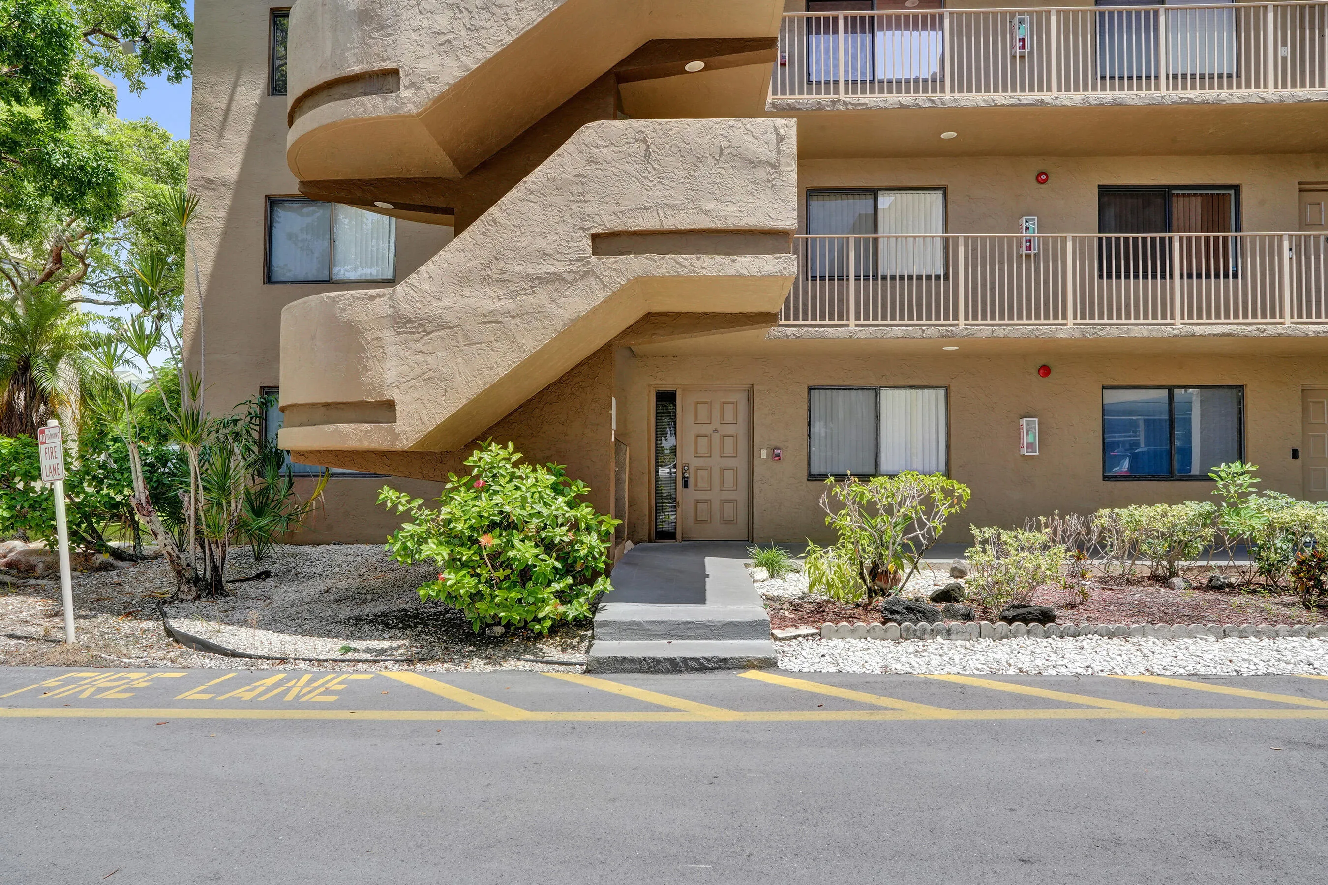 Multi-story stucco exterior with sliding glass doors, exterior railings, and an entry door with panel details