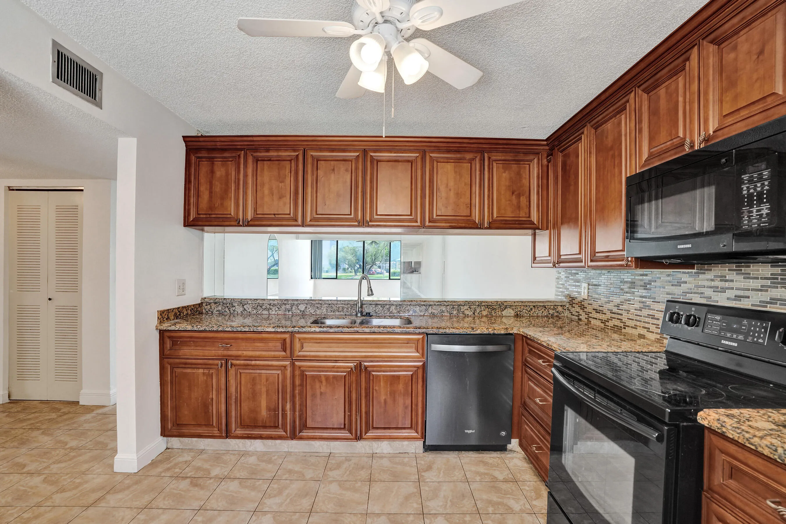 Kitchen featuring wood cabinetry, granite countertops, tile flooring, and a mosaic tile backsplash