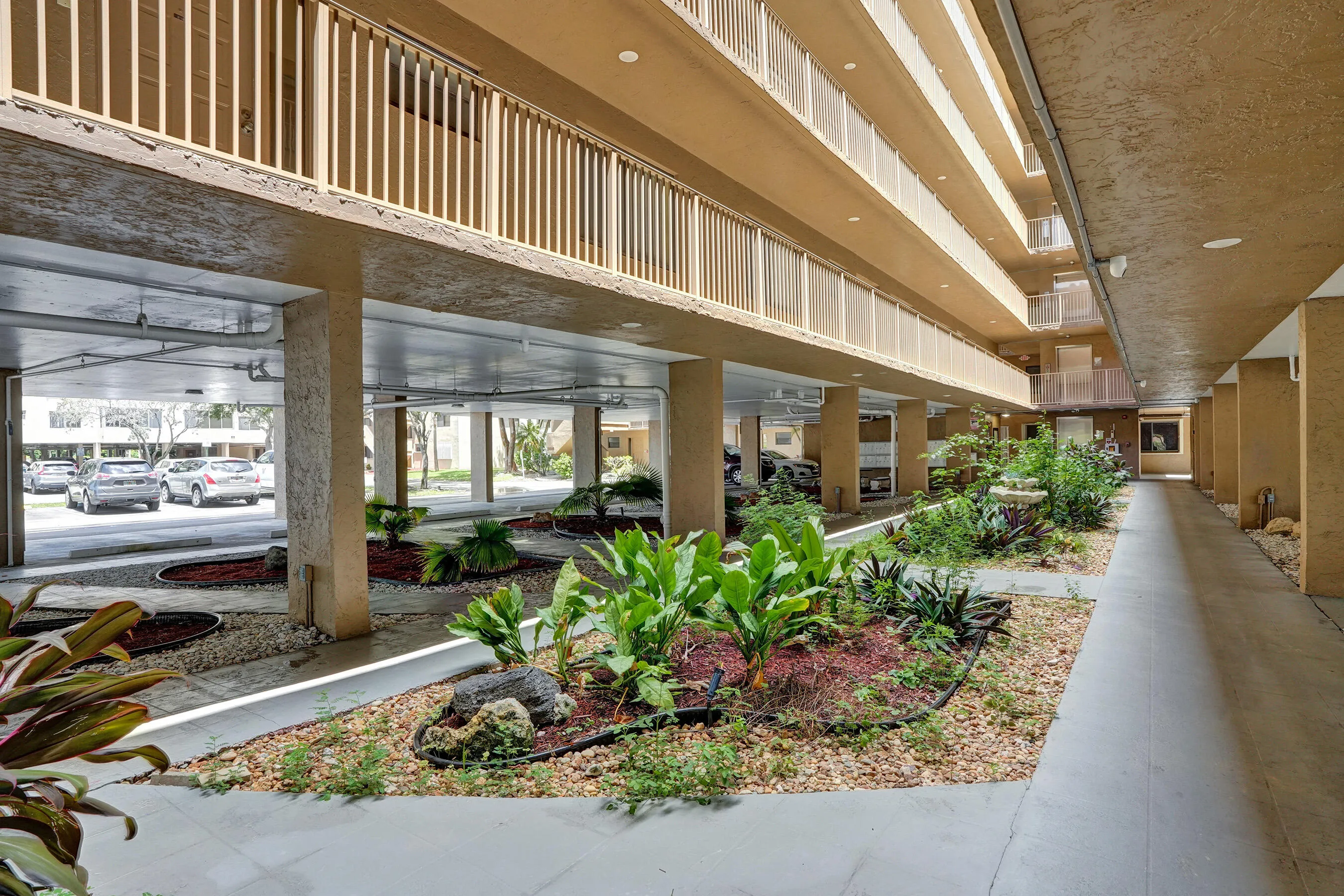 Covered walkway with integrated landscaping, featuring a variety of plantings and decorative rock elements