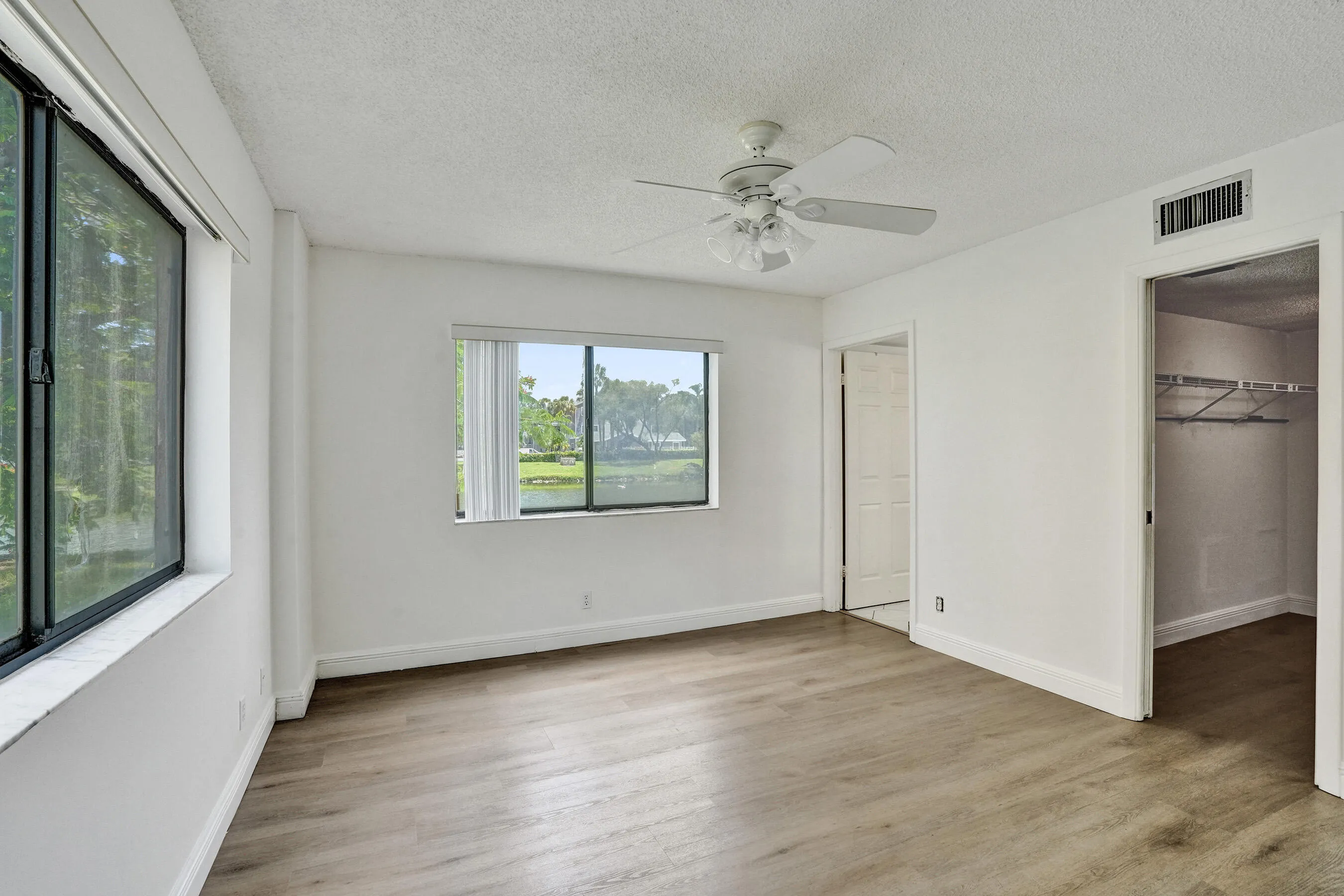Wood-finish flooring, white walls, and a ceiling fan
