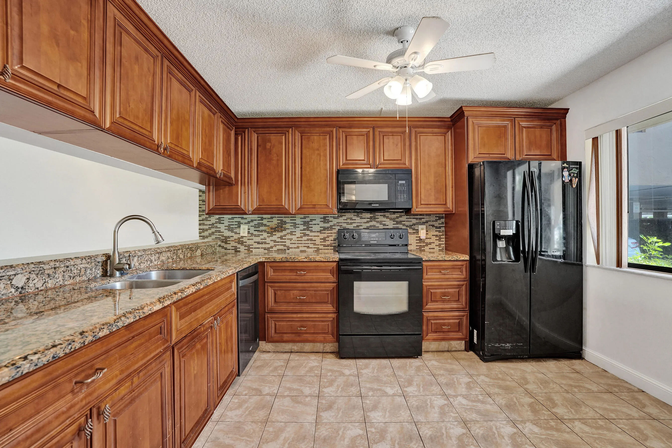 Kitchen featuring wood cabinetry, granite countertops, patterned tile backsplash, and ceramic tile flooring