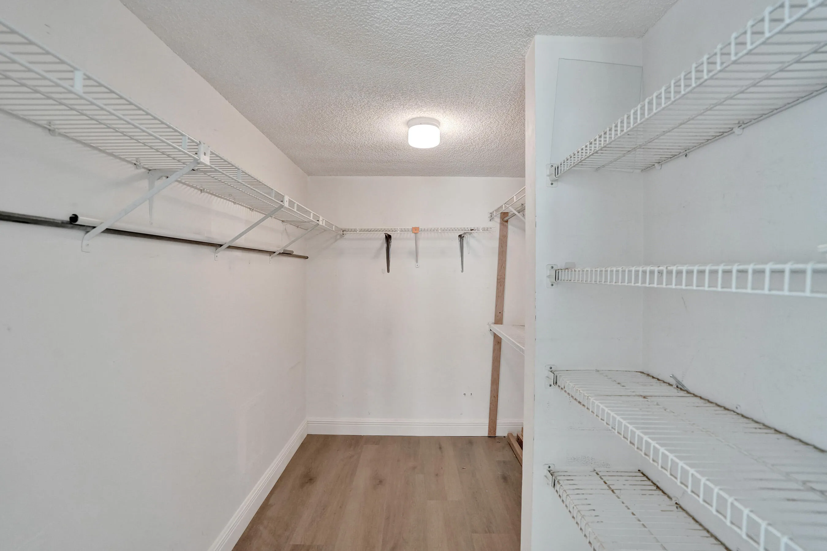 Spacious closet with wire shelving, hanging rods, recessed lighting, and wood-finish flooring