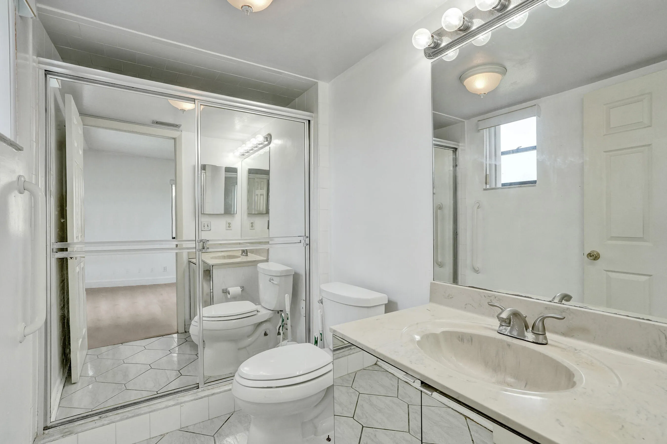 Bathroom featuring a vanity with an integrated sink, polished chrome faucet, full-width mirror, and a shower enclosure with a sliding glass door