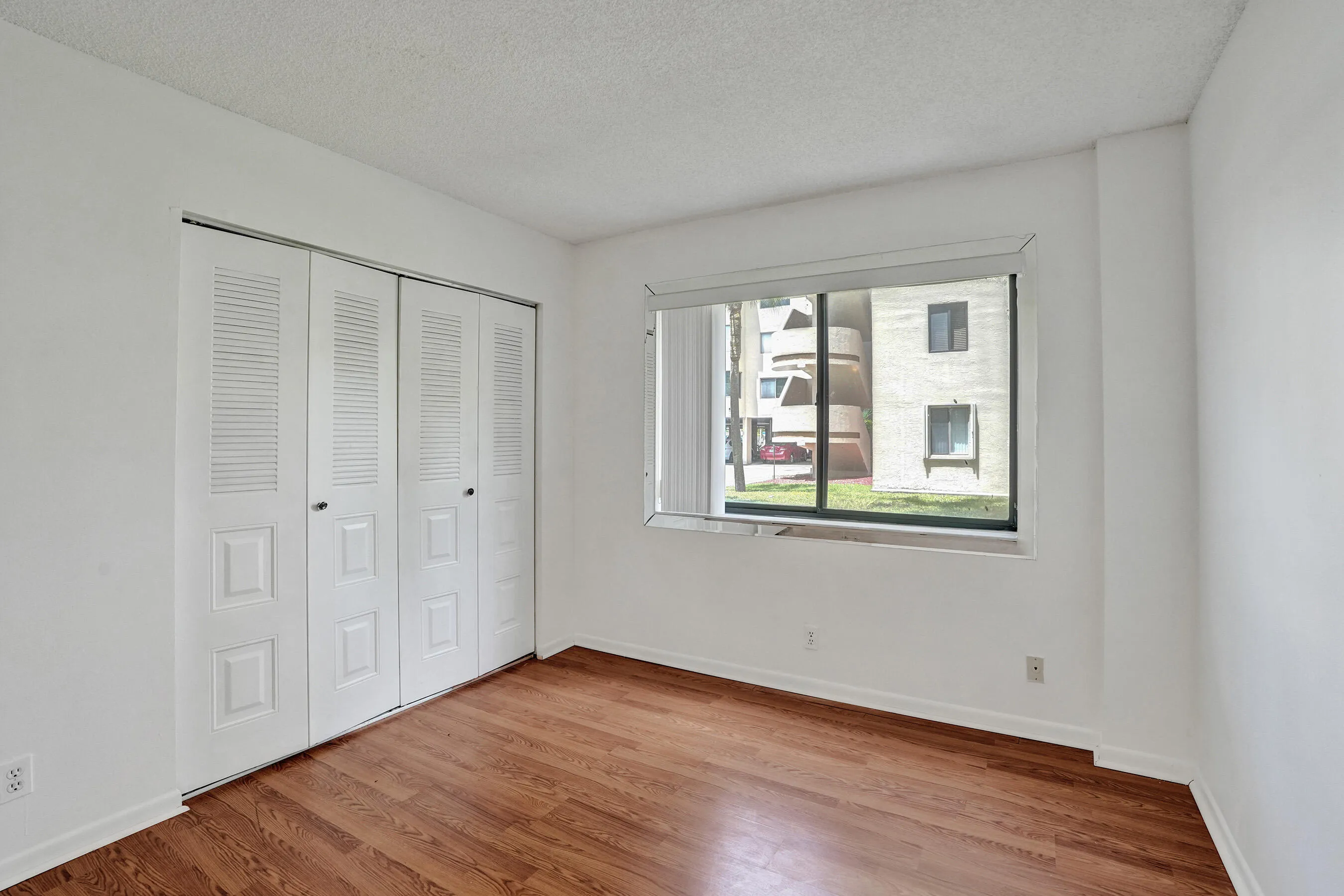 Expansive window, wood-finish flooring, and white bi-fold closet doors