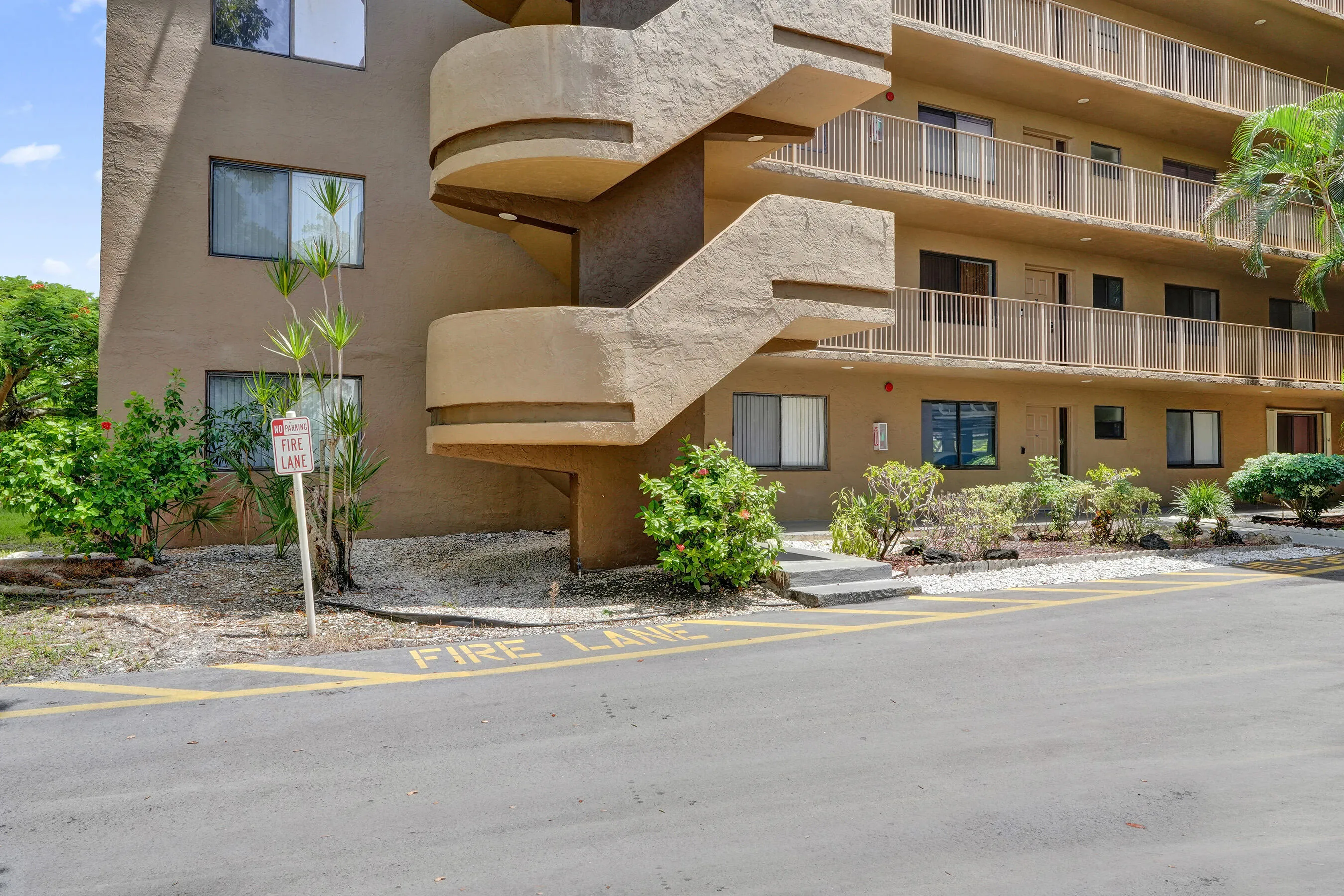 Exterior featuring a multi-story structure with prominent spiral staircases, multiple balconies with railings, and ground-level landscaping