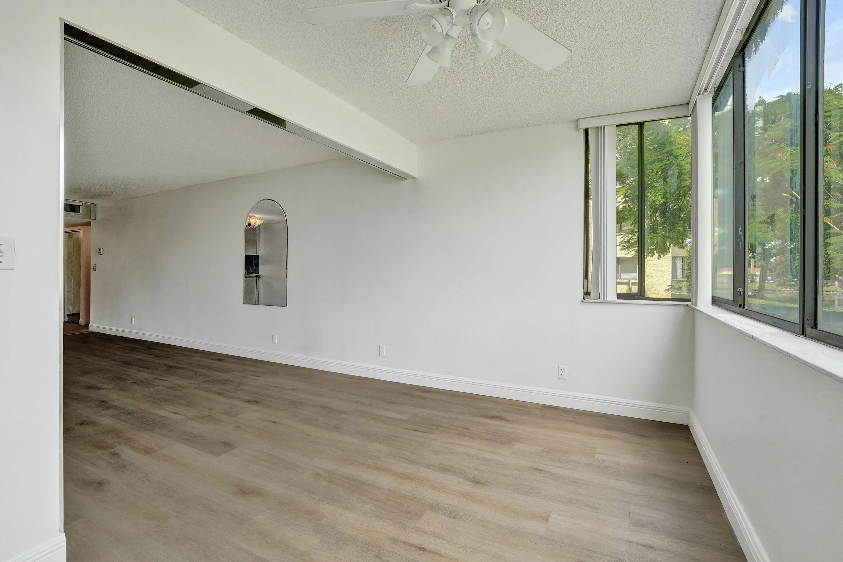 Wood-finish flooring, white walls, and a ceiling fan with integrated lighting