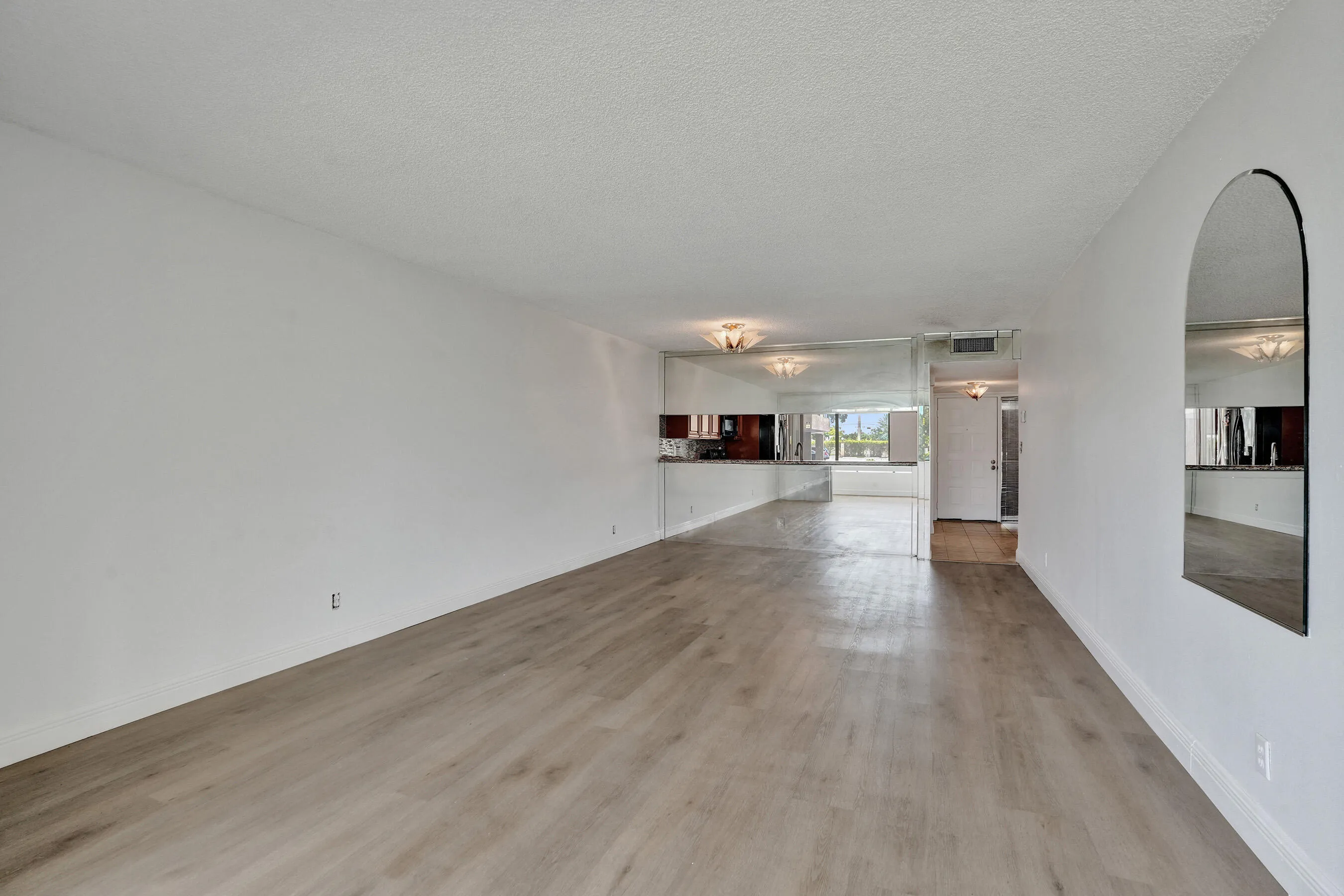 Light-toned wood-finish flooring, white walls, and recessed lighting