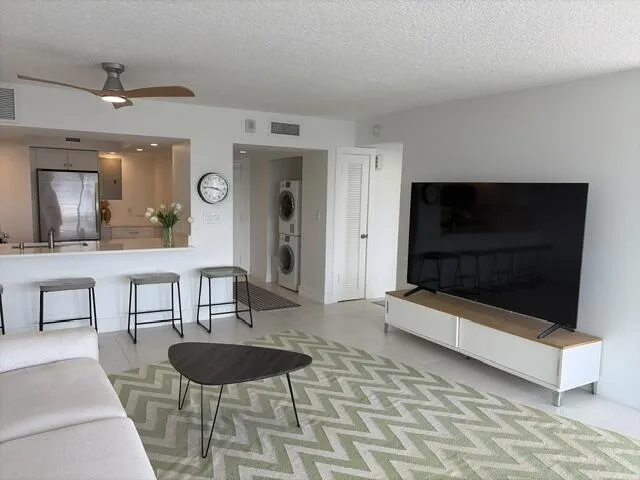Kitchen pass-through with breakfast bar, integrated stainless steel refrigerator, white shaker-style cabinetry, and a ceiling fan with integrated lighting
